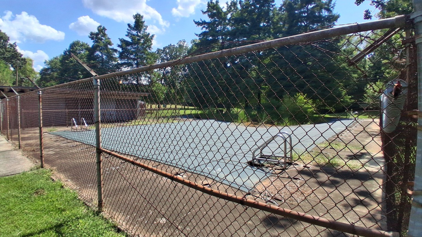 Before: the rusted fence line of the closed Norwood pool, restored with clean fencing and a pool full of swimmers